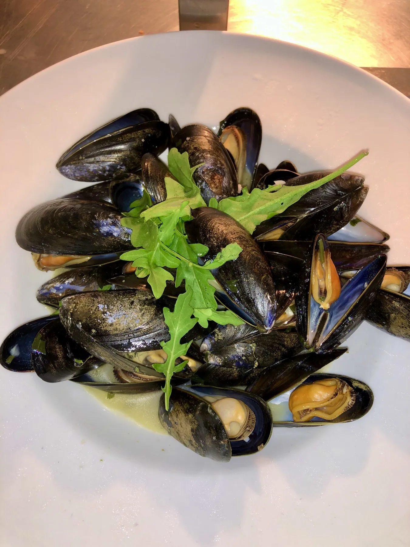 A bowl of moules mariniere with rocket